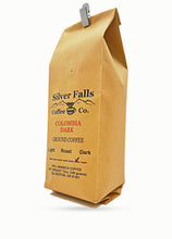 Load image into Gallery viewer, A brown kraft paper coffee bag with a silver clip at the top, featuring the Silver Falls Coffee Co. logo and 'COLOMBIA DARK' text on a white background.